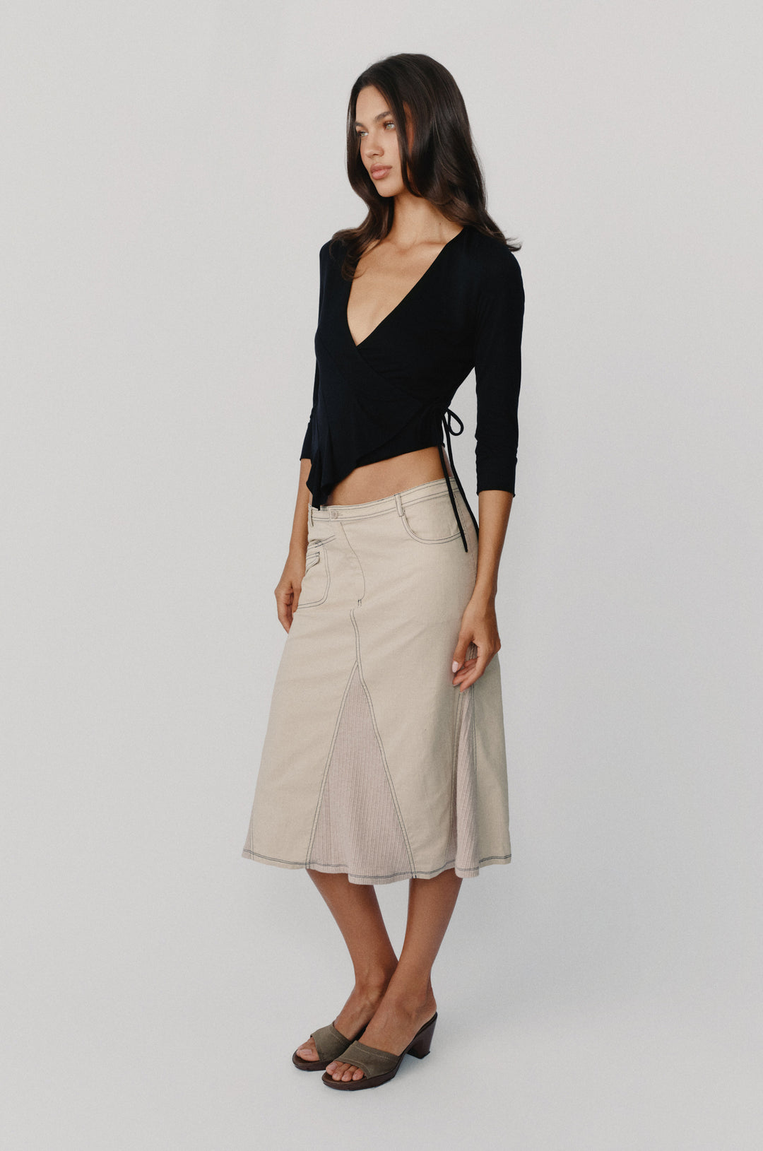 Taupe low-rise midi skirt with asymmetric pockets, contrast topstitching, and ribbed panel detailing.