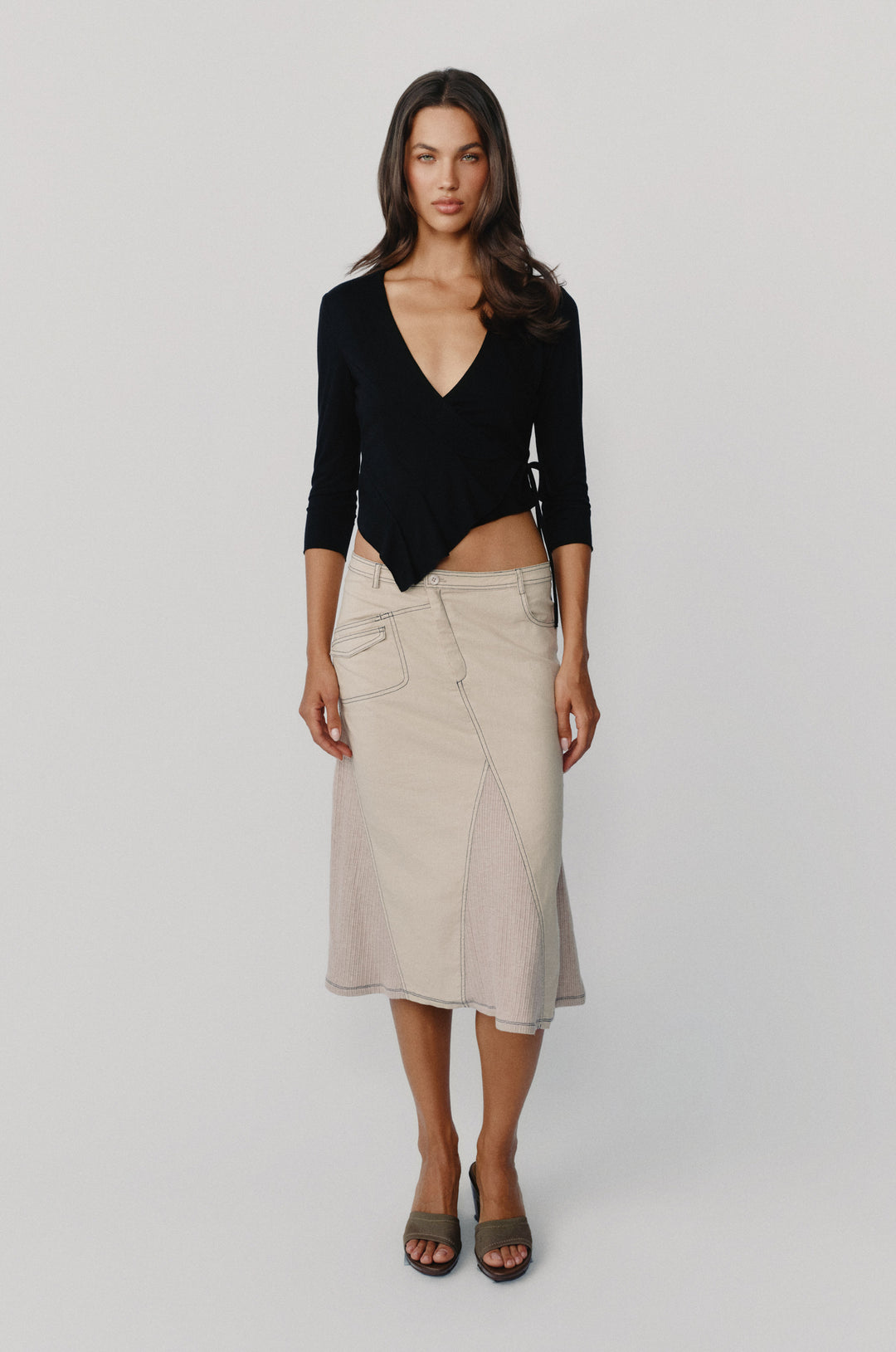 Taupe low-rise midi skirt with asymmetric pockets, contrast topstitching, and ribbed panel detailing.