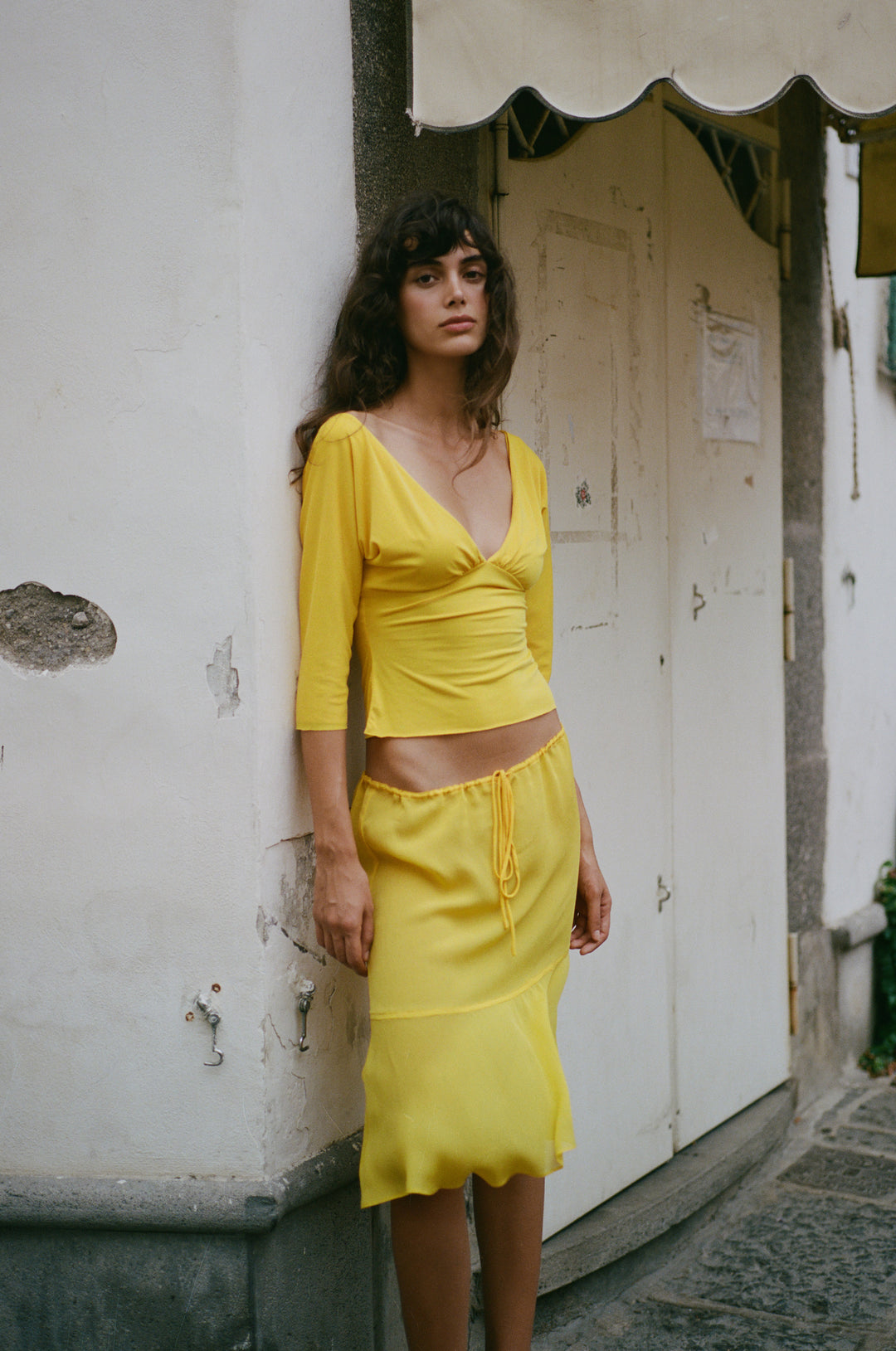 Golden yellow sheer low-rise Pali skirt with an adjustable drawstring waist and flowy curved hemline.