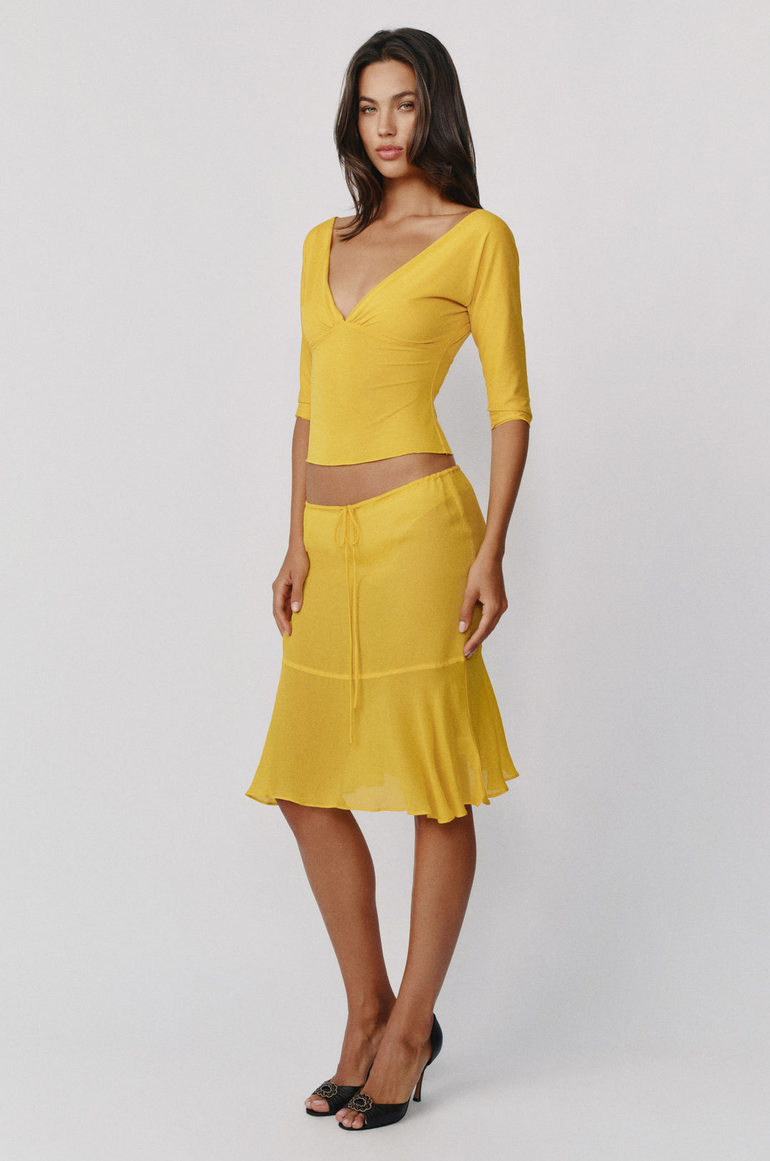 Golden yellow sheer Pali skirt with a low-rise adjustable drawstring waist and a flowy drop seam curved hemline.