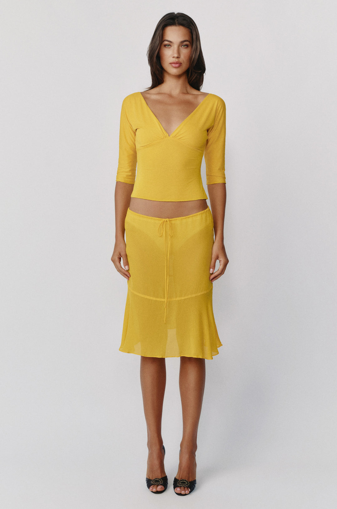 Golden yellow sheer Pali skirt with a low-rise adjustable drawstring waist and a flowy, curved drop-seam hemline.