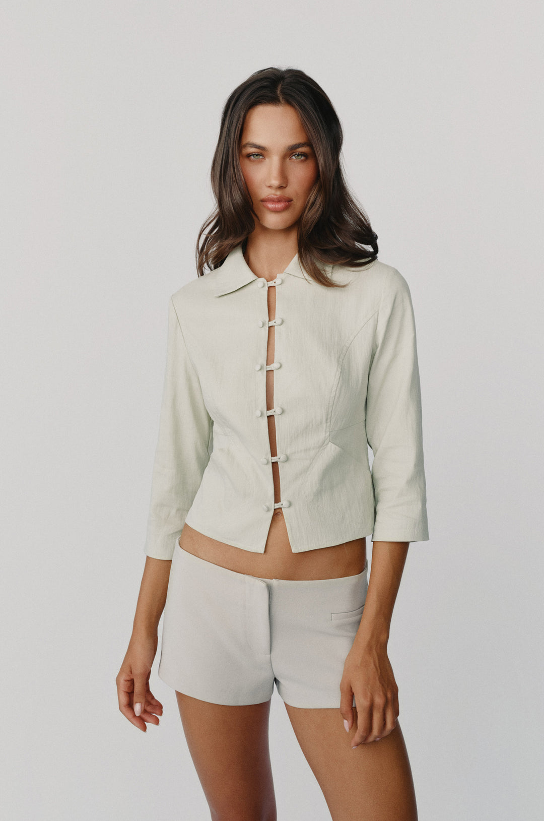 Dusty sage collared Reya jacket with 3/4 sleeves and a front loop button closure worn with matching shorts.