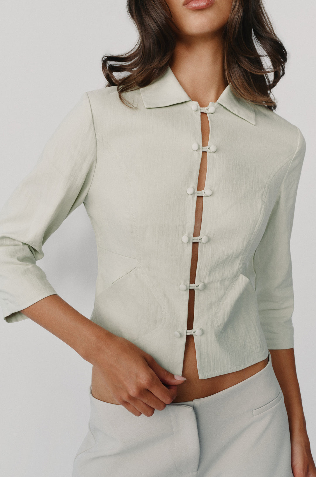 Dusty sage collared jacket with 3/4 sleeves and a loop button-front closure worn by a model.