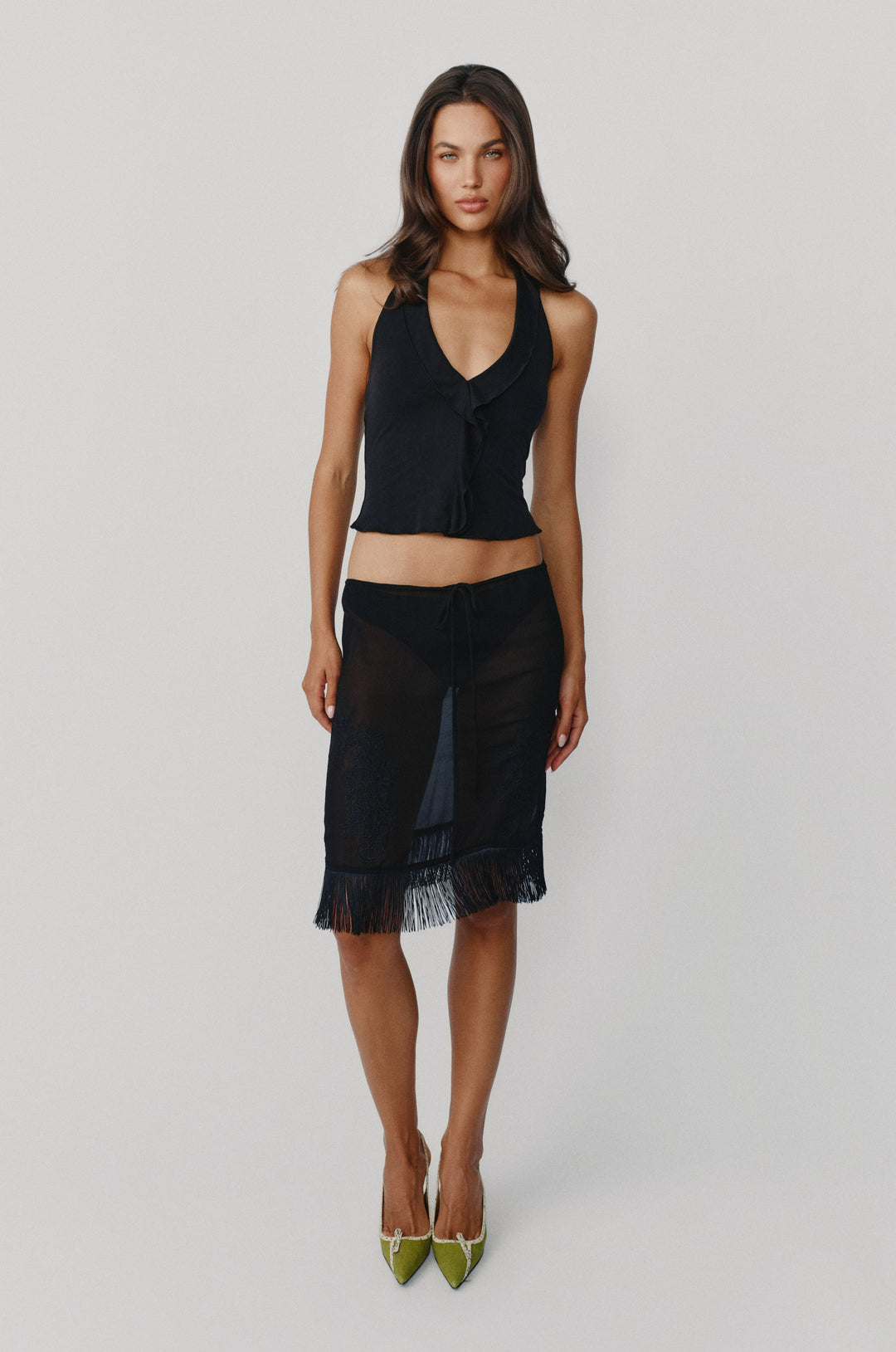 Black halter-style Ruby top featuring a ruffle-trim neckline and center front, paired with a sheer fringed skirt.