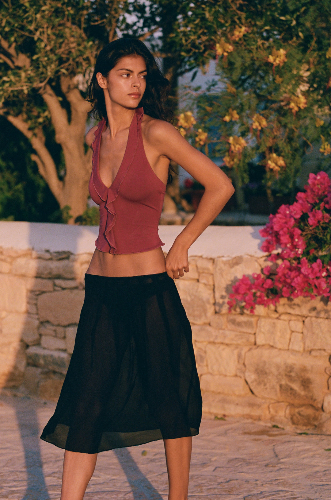Plum halter-style Ruby top with ruffle-trim neckline and open back, paired with a black sheer skirt outdoors.