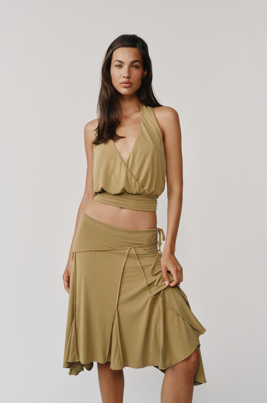 Model wearing an olive halter wrap top with a V-neckline and fitted hem band.