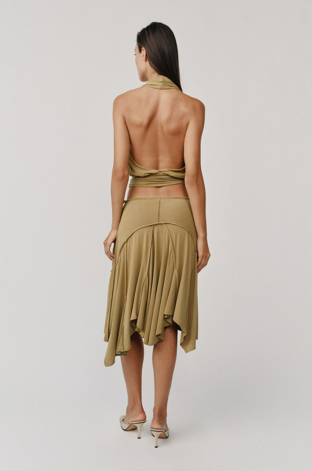 Woman from behind wearing an olive halter wrap top with a V-neck and fitted hem, paired with a matching skirt.