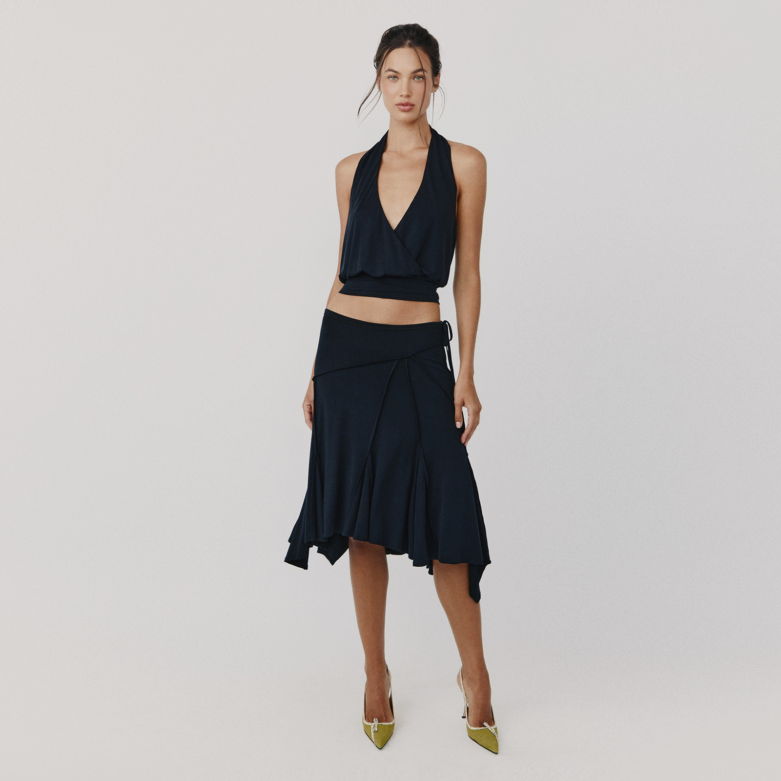 Woman wearing a black halter top and skirt set on a plain background