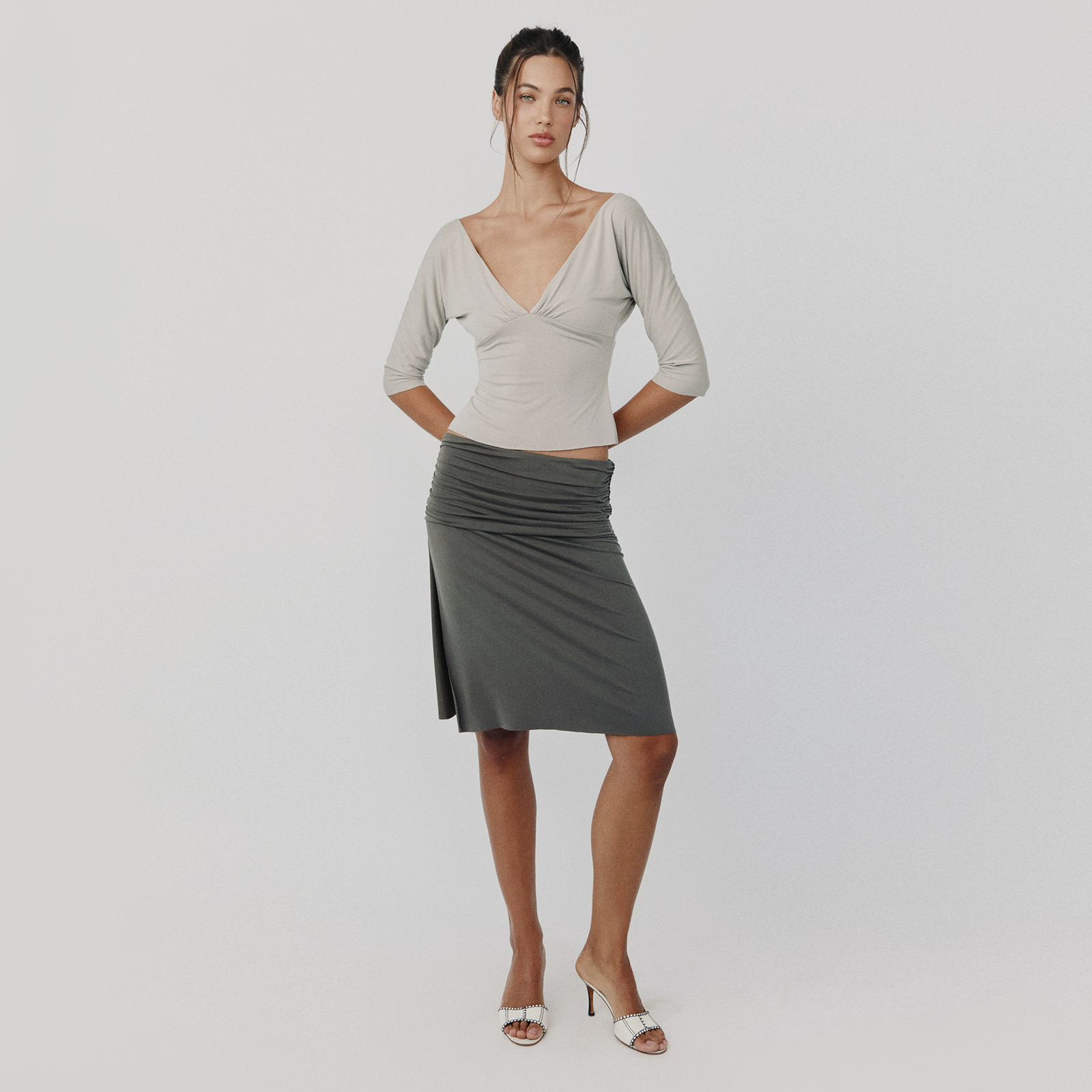 Woman wearing a gray top and skirt on a plain background