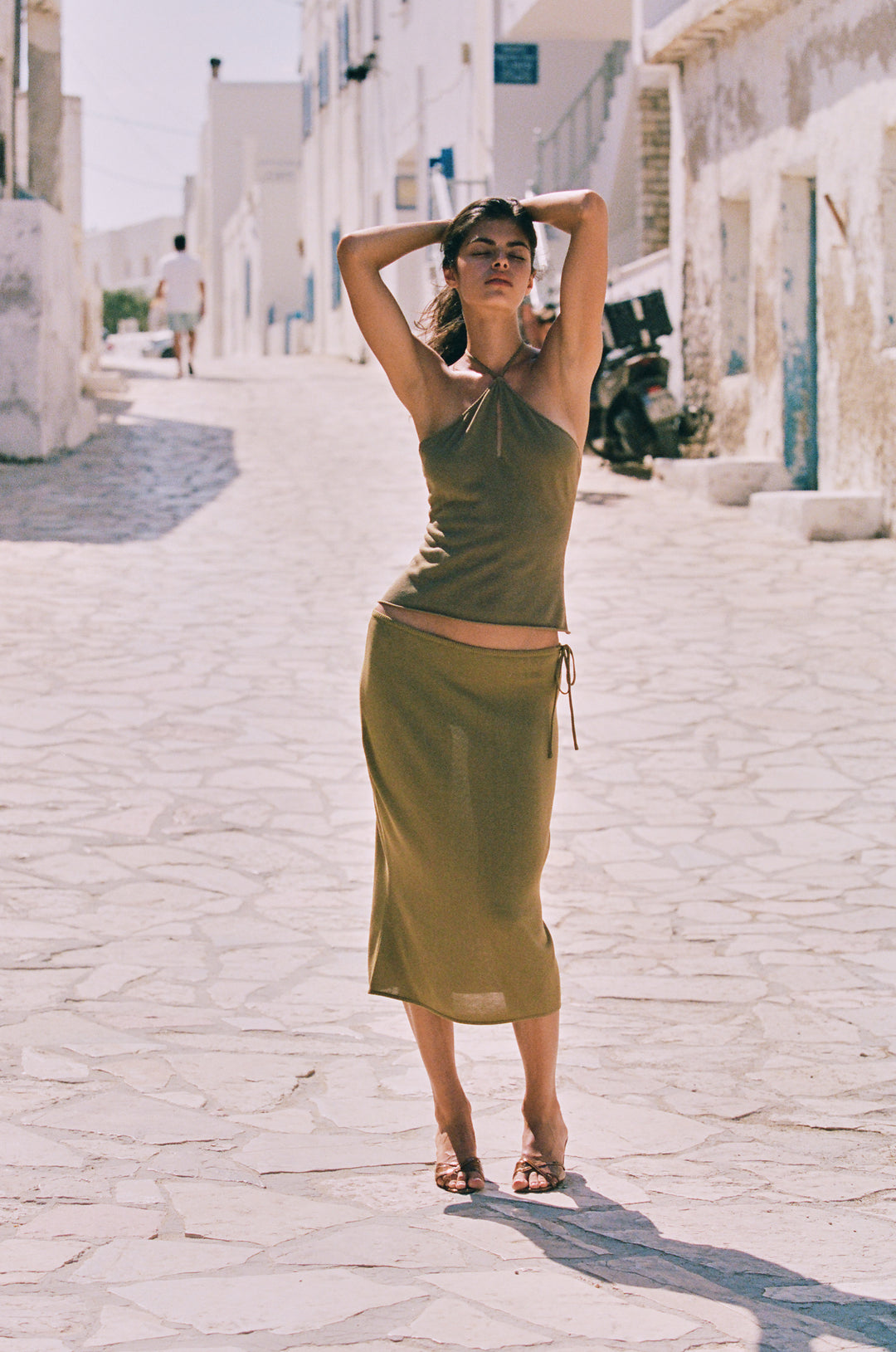 Olive green low-rise midi skirt with an adjustable side-tie waistband and a soft curved hemline.