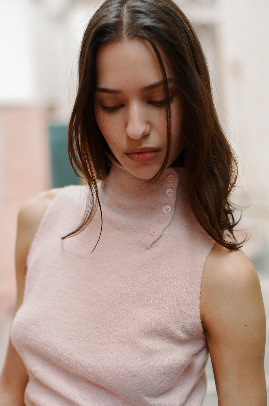 Model wearing a pink knitted Trinity Top with a high neck, button-up closure, and keyhole cutout.