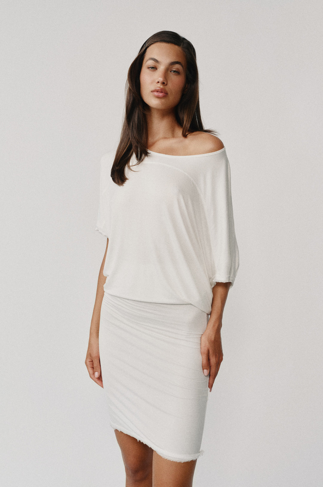 White Vinnie off-the-shoulder midi dress with a relaxed neckline, fitted body, and raw edge hem.
